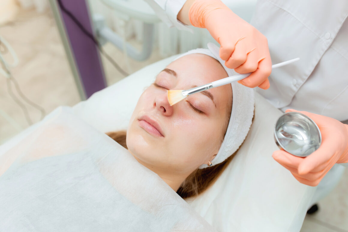 a specialist applying chemical peel product on a patient face