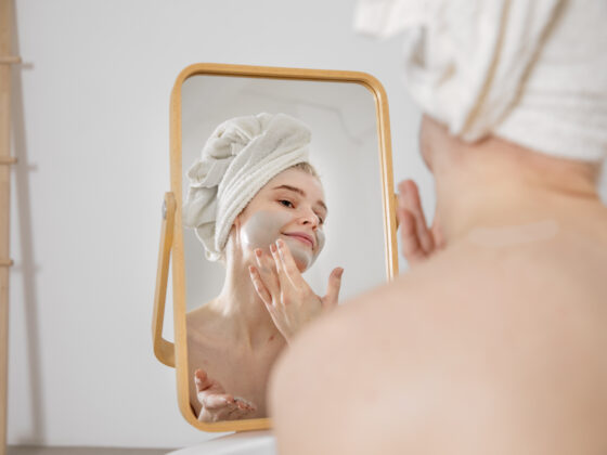 Woman examining her skin type in the mirror.