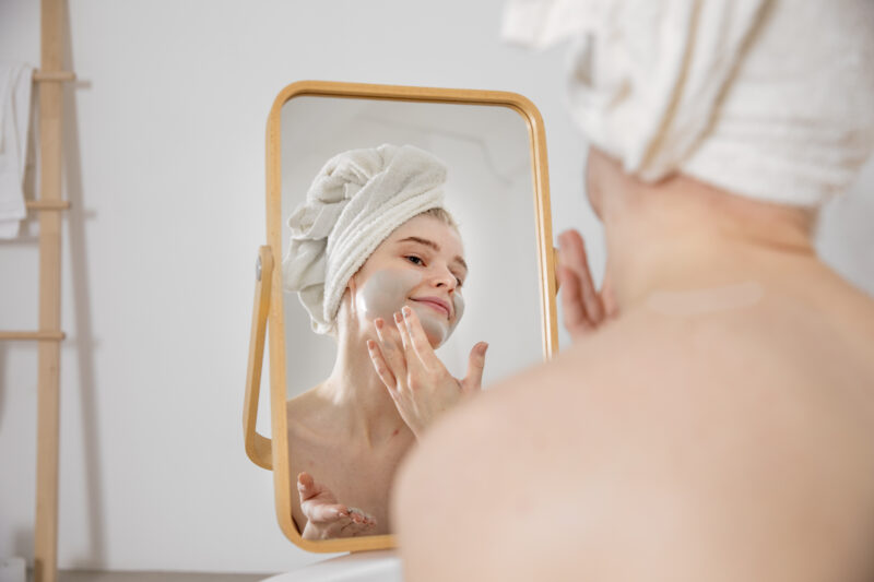 Woman examining her skin type in the mirror.