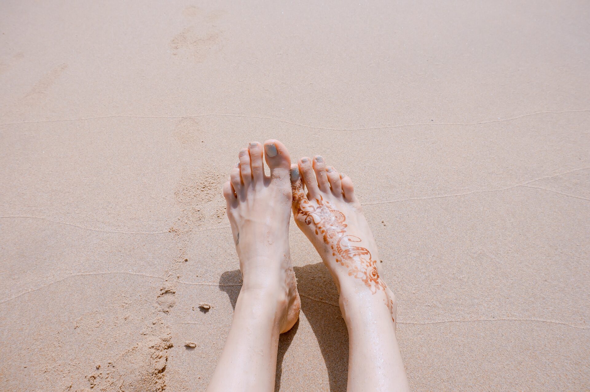 Woman's well-cared-for smooth feet on a soft Focus at a beach sand