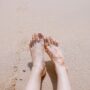 Woman's well-cared-for smooth feet on a soft Focus at a beach sand