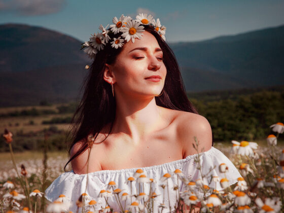 beautiful woman showing her beauty in a daisy field with flowers after embracing Spring Skin Renewal Techniques